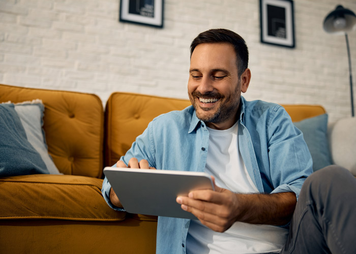 mann-formular-barrierefrei Zufriedener Mann nutzt Tablet im Wohnzimmer – entspanntes Arbeiten oder Surfen auf dem Sofa